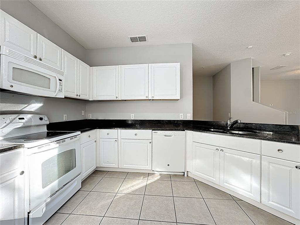 1500 Broken Oak Drive, Unit 25B Winter Garden, FL 34787 - Photo 29 of 62 a kitchen with granite countertop white cabinets and white appliances