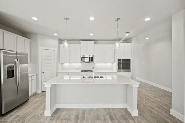 a view of kitchen with kitchen island stainless steel appliances sink refrigerator and microwave