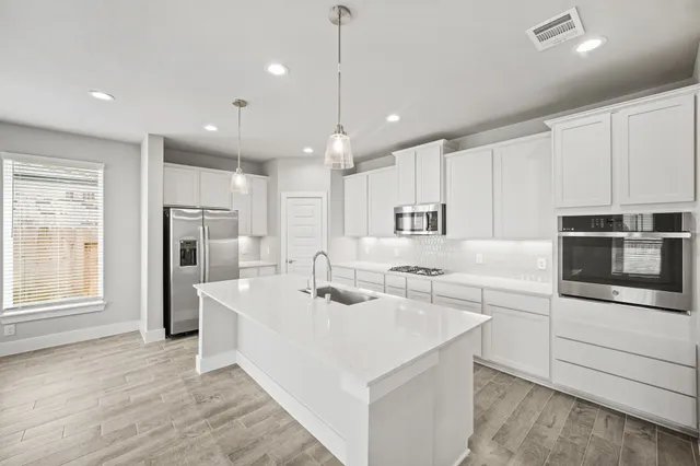 a kitchen with stainless steel appliances kitchen island granite countertop a sink and a refrigerator