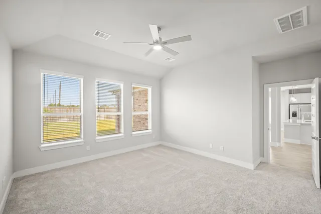 an empty room with windows and ceiling fan