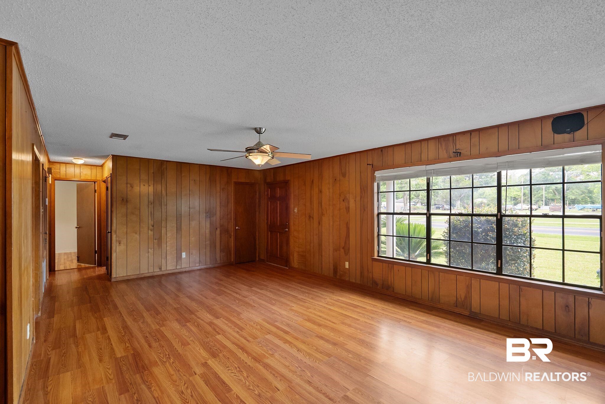 716 North Cedar Street Foley, AL 36535 - Photo 4 of 25 Spacious interior featuring wood-finish flooring, wood-paneled walls, a multi-pane window with blinds, and a ceiling fan with integrated lighting