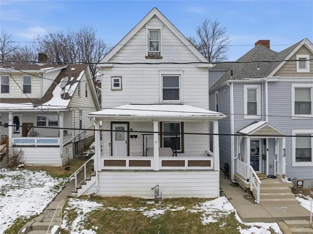 a view of a white house with large windows and a small yard