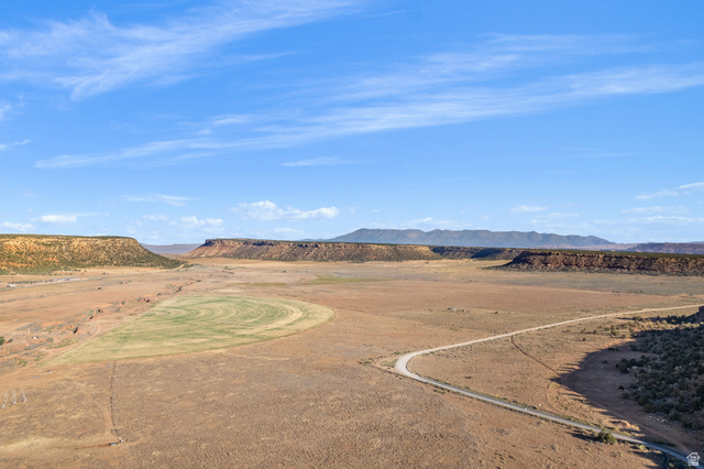 Gooseberry Way Apple Valley, UT 84737 - Photo 21 of 24 Expansive desert landscape featuring a winding dirt road, cultivated agricultural fields, and distant mesa formations under a clear blue sky