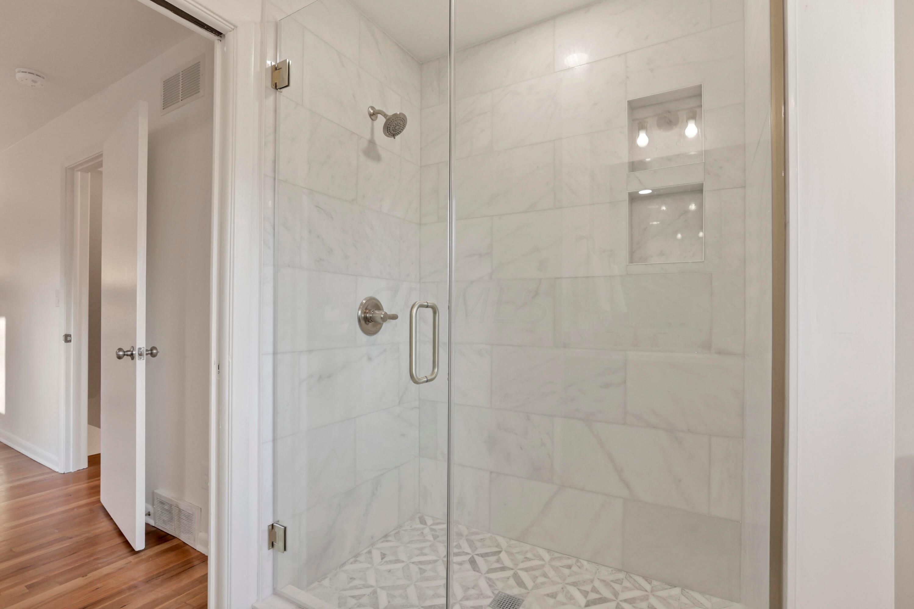 2275 Haverford Road Columbus, OH 43220 - Photo 29 of 57 The en suite bathroom with a double vanity sink, new fixtures, updated lighting, tile shower with built-in niche and custom glass door.