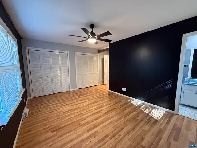 a view of empty room with wooden floor and fan