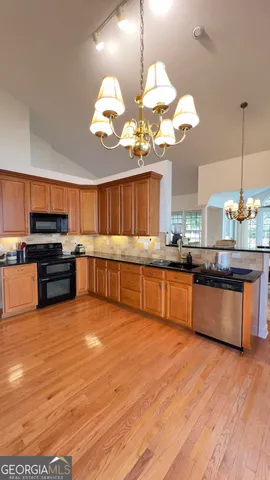 a large kitchen with stainless steel appliances granite countertop a stove and a wooden floor