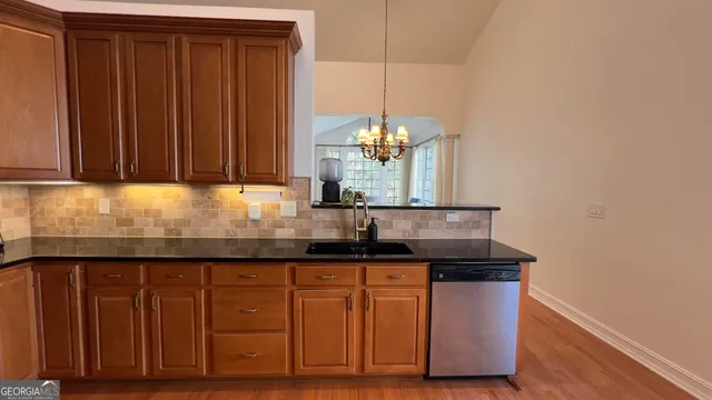 a kitchen with granite countertop a sink cabinets and wooden floor