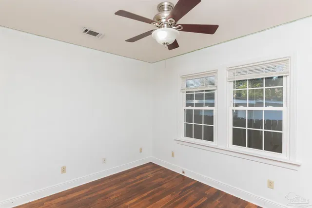 a view of empty room with wooden floor and fan
