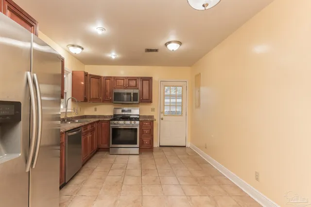 a large kitchen with stainless steel appliances granite countertop a stove and a refrigerator