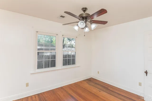an empty room with wooden floor closet and windows