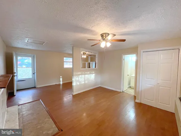 a view of an empty room with window and wooden floor