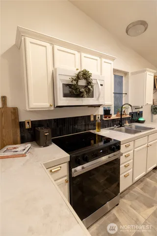 a living room with stainless steel appliances kitchen island granite countertop a table chairs and a refrigerator