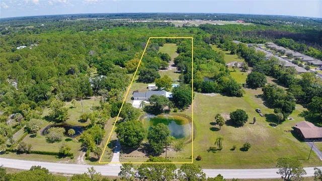 an aerial view of a residential houses with outdoor space and trees