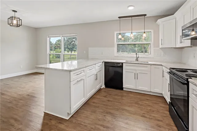 a kitchen with white cabinets appliances a sink and a window