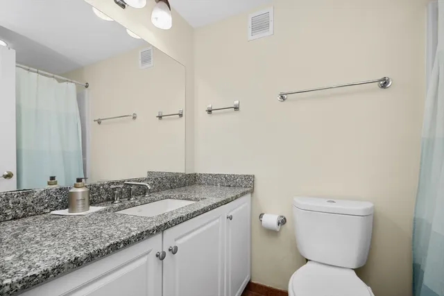 a bathroom with a granite countertop sink a toilet and a mirror
