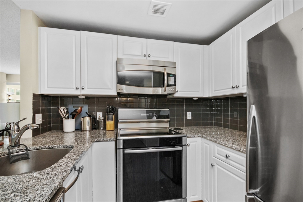 8 Museum Way, Unit 504 Cambridge, MA 02141 - Photo 7 of 30 a kitchen with granite countertop a sink a stove and cabinets