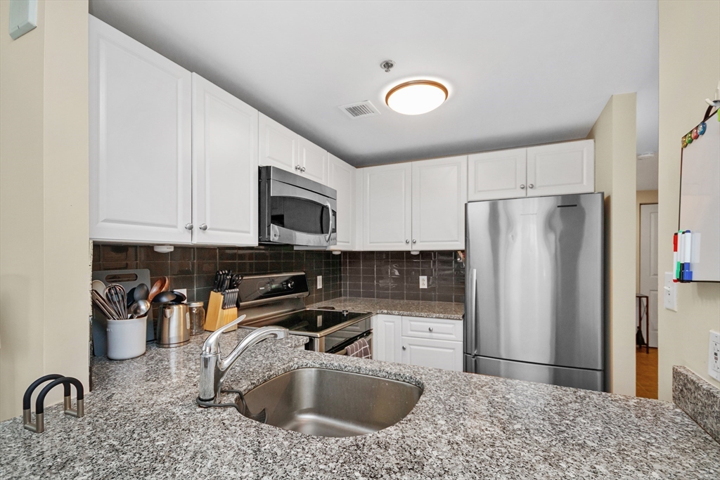 8 Museum Way, Unit 504 Cambridge, MA 02141 - Photo 8 of 30 a kitchen with stainless steel appliances granite countertop a sink a stove a refrigerator a microwave and cabinets