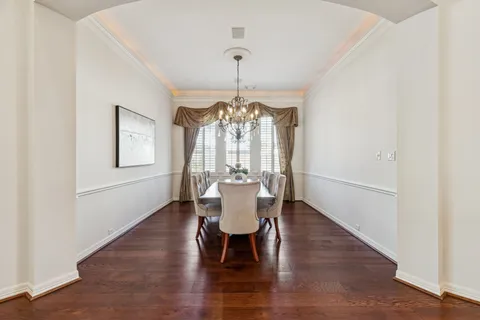 a dining room with wooden floor a chandelier a wooden table and chairs