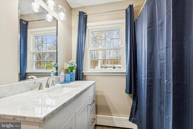 a bathroom with a granite countertop sink a toilet and a window
