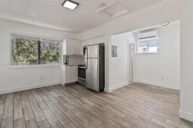 a view of a kitchen with wooden floor electronic appliances and windows