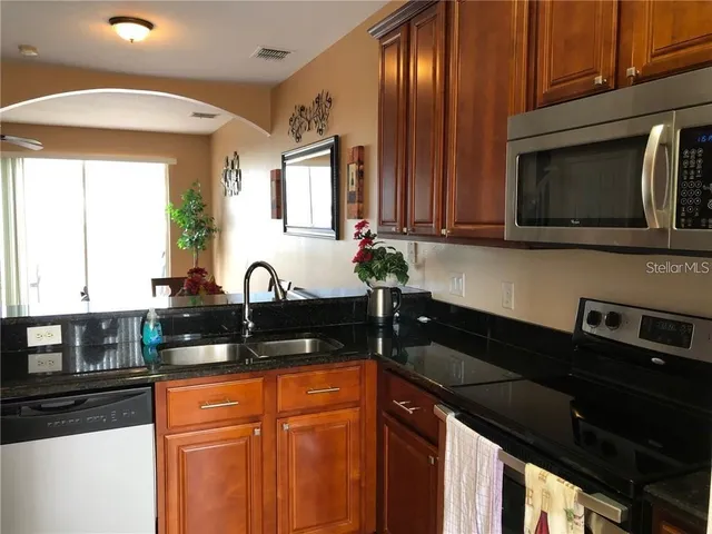 a kitchen with granite countertop stainless steel appliances a sink stove top oven and microwave