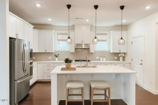 a kitchen with stainless steel appliances granite countertop a sink a stove a refrigerator and island with wooden floor