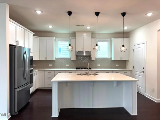 a large kitchen with stainless steel appliances granite countertop a sink a stove and a refrigerator