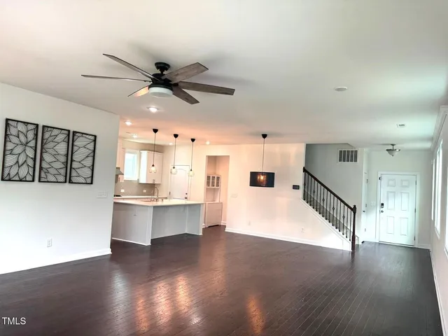 a view of an empty room with window and wooden floor