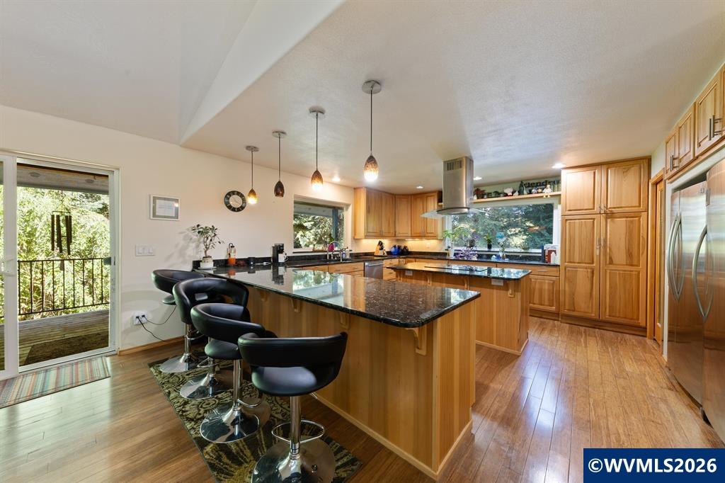6100 Teal Creek Road Dallas, OR 97338 - Photo 10 of 41 a kitchen with stainless steel appliances granite countertop a table chairs stove and wooden floor