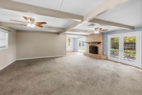 an empty room with fireplace fan and windows
