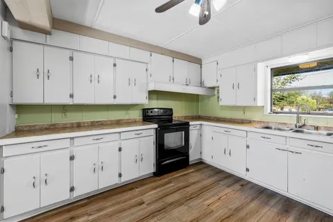 a kitchen with granite countertop white cabinets white stainless steel appliances and a sink
