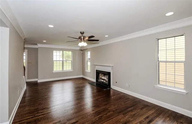 an empty room with wooden floor chandelier and windows