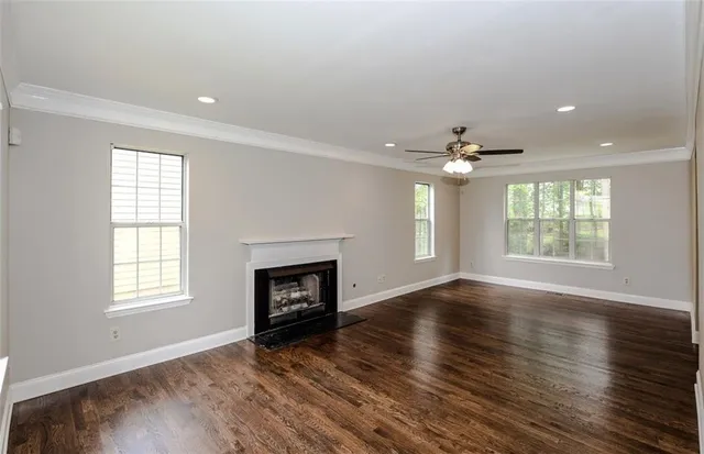 an empty room with wooden floor fireplace and windows