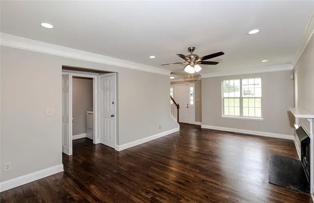 a view of an empty room with wooden floor and a ceiling fan