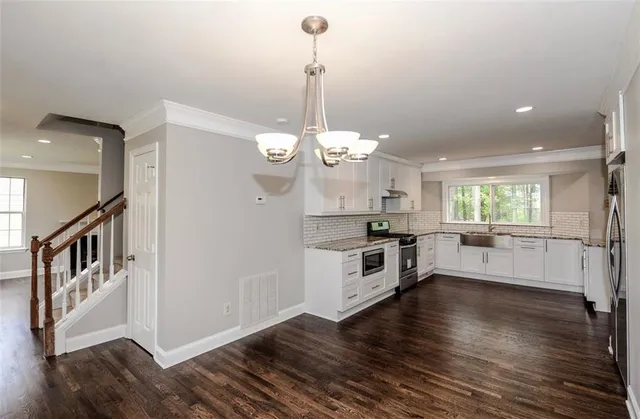 a kitchen with stainless steel appliances a chandelier and wooden floor