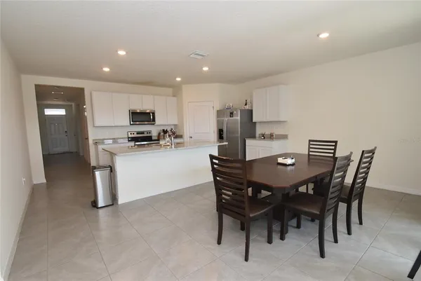 a kitchen with stainless steel appliances kitchen island granite countertop a table chairs and a refrigerator