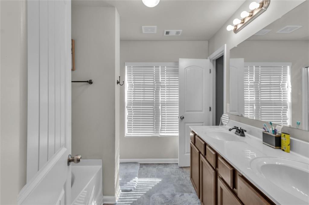 171 Pinnacle Point Court Dallas, GA 30132 - Photo 19 of 26 a bathroom with a granite countertop sink a large mirror and a bathtub