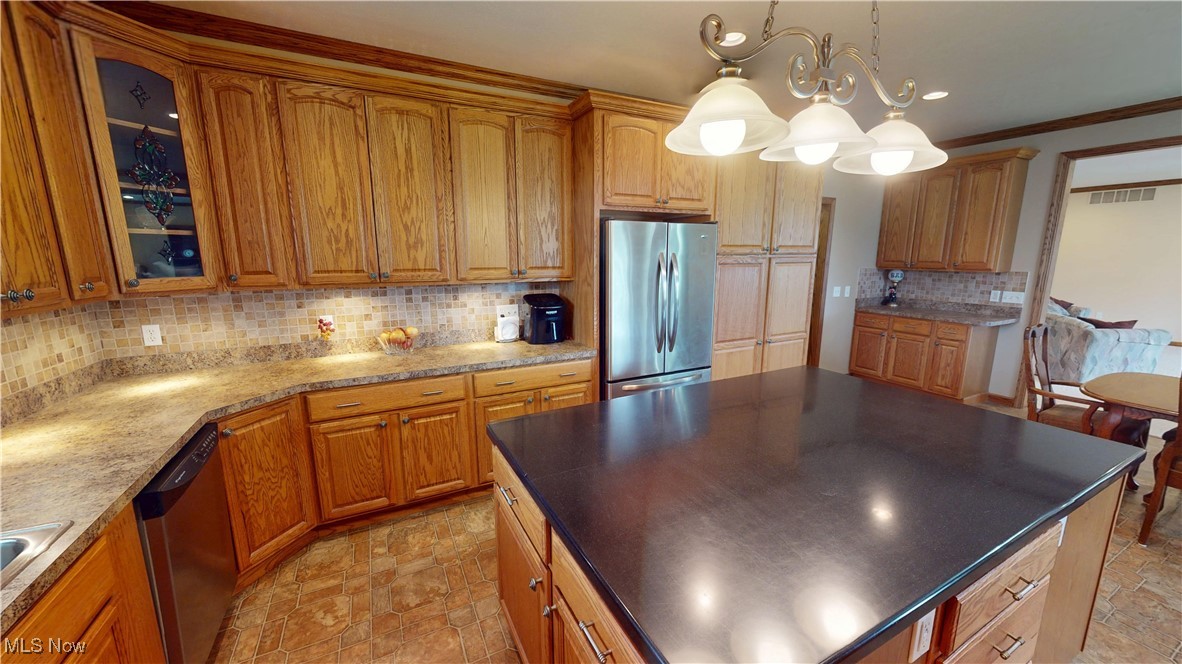 10323 Smith Road Litchfield, OH 44253 - Photo 14 of 50 Kitchen featuring glass insert cabinets, tasteful backsplash, appliances with stainless steel finishes, and brown cabinetry