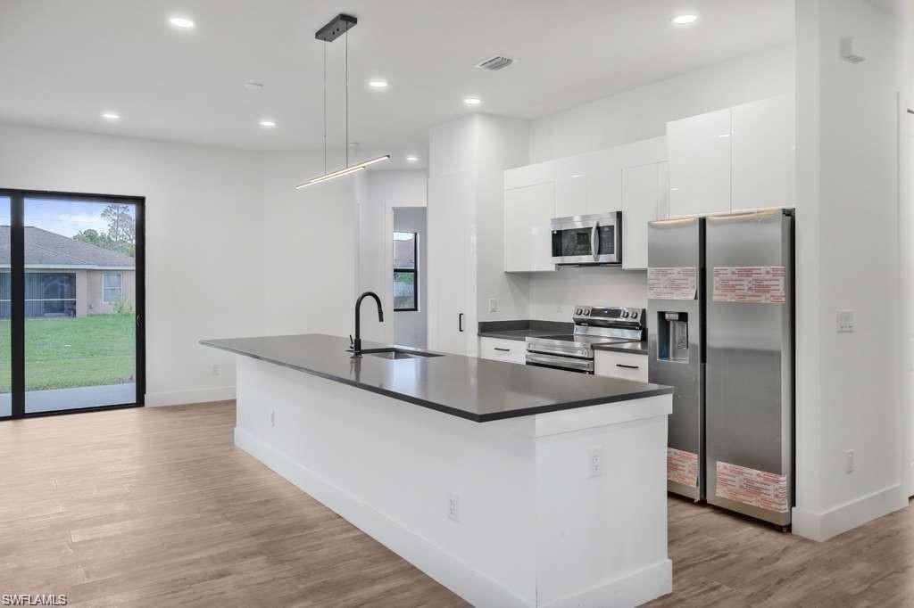 812 Homestead Road South Lehigh Acres, FL 33974 - Photo 3 of 21 a kitchen with stainless steel appliances granite countertop a sink a stove and a refrigerator