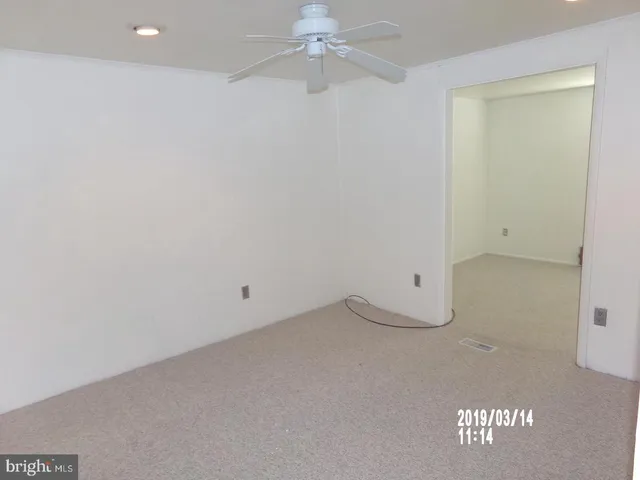 an empty room with a ceiling fan and carpet