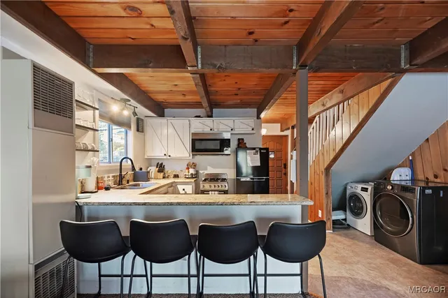 a dining room with stainless steel appliances kitchen island granite countertop a table chairs and a wooden floor