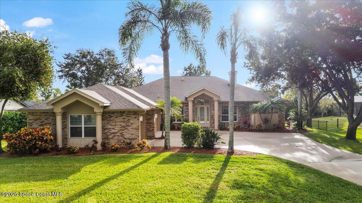 4245 Windover Way Melbourne, FL 32934 - Photo 27 of 50 a front view of a house with a garden and trees