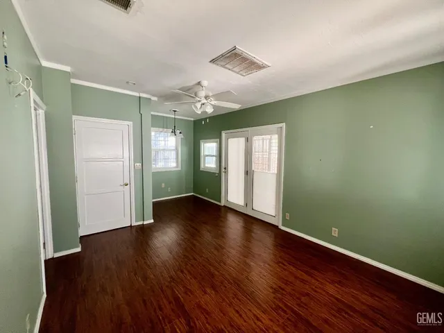 a view of an empty room with wooden floor and a window