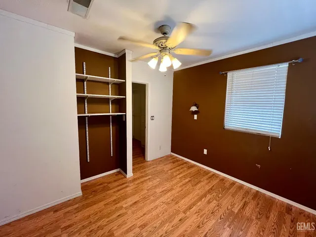 a view of empty room with wooden floor and fan