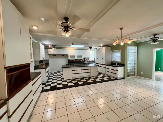 a large kitchen with stainless steel appliances kitchen island granite countertop a refrigerator and a stove top oven