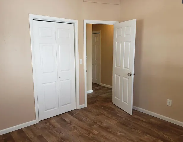 an empty room with wooden floor and closet area