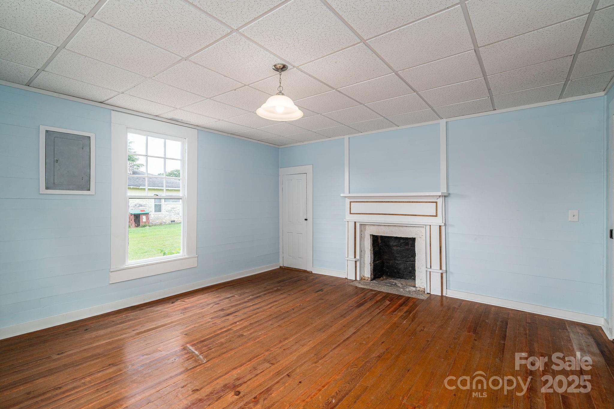 5746 Casar Road Casar, NC 28020 - Photo 16 of 24 an empty room with windows fireplace and wooden floor