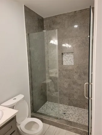 a bathroom with a granite countertop shower and a toilet