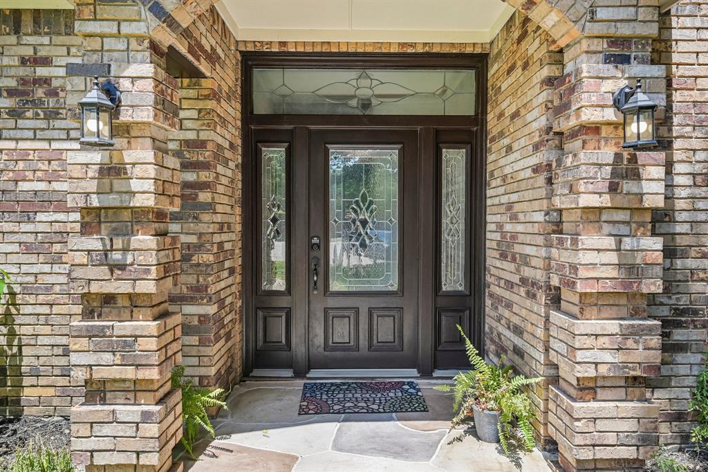 925 Spring Brook Drive Allen, TX 75002 - Photo 2 of 30 Welcoming entry features a dark-finish steel door with decorative glass panels and sidelights, framed by multi-toned brick masonry in warm earth tones