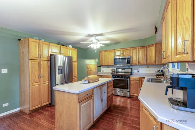 a kitchen with stainless steel appliances granite countertop a stove top oven a refrigerator and a granite counter tops with wooden floors